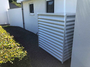 witte geluidskast warmtepomp tegen wit huis